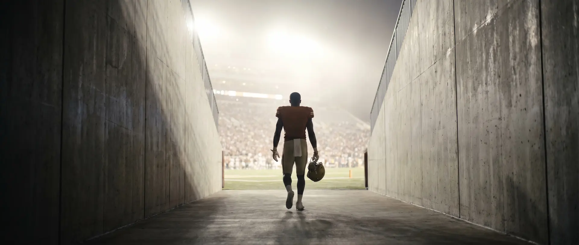 Athlete walking through stadium tunnel toward the field lights